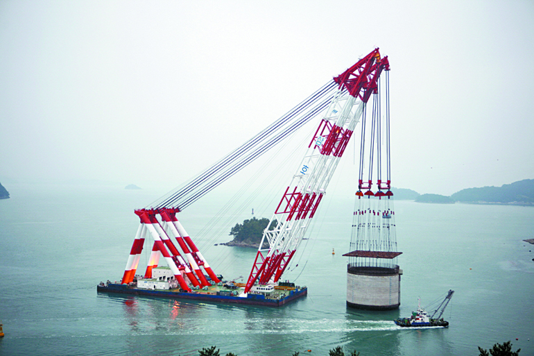 해상 크레인으로 거치식 콘크리트 우물통을 설치하고 있다.