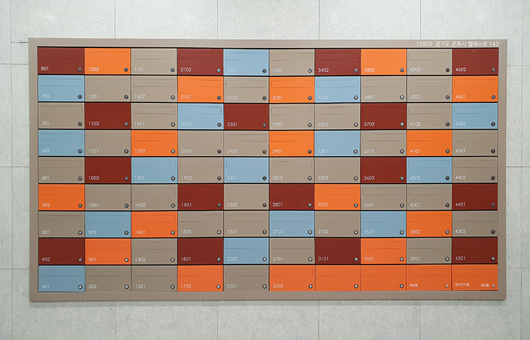 격자 무늬 양식의 와인색과 주황색, 하늘색을 우편함에 적용한 시그니처 월의 모습 - 현대건설은 시그니처 월(Signature Wall)을 통해 세대별로 다른 색상의 우편함을 소유하는 신선한 경험을 선사한다 